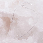 dainty italian sterling silver fine chain anklet laying on a white crystal