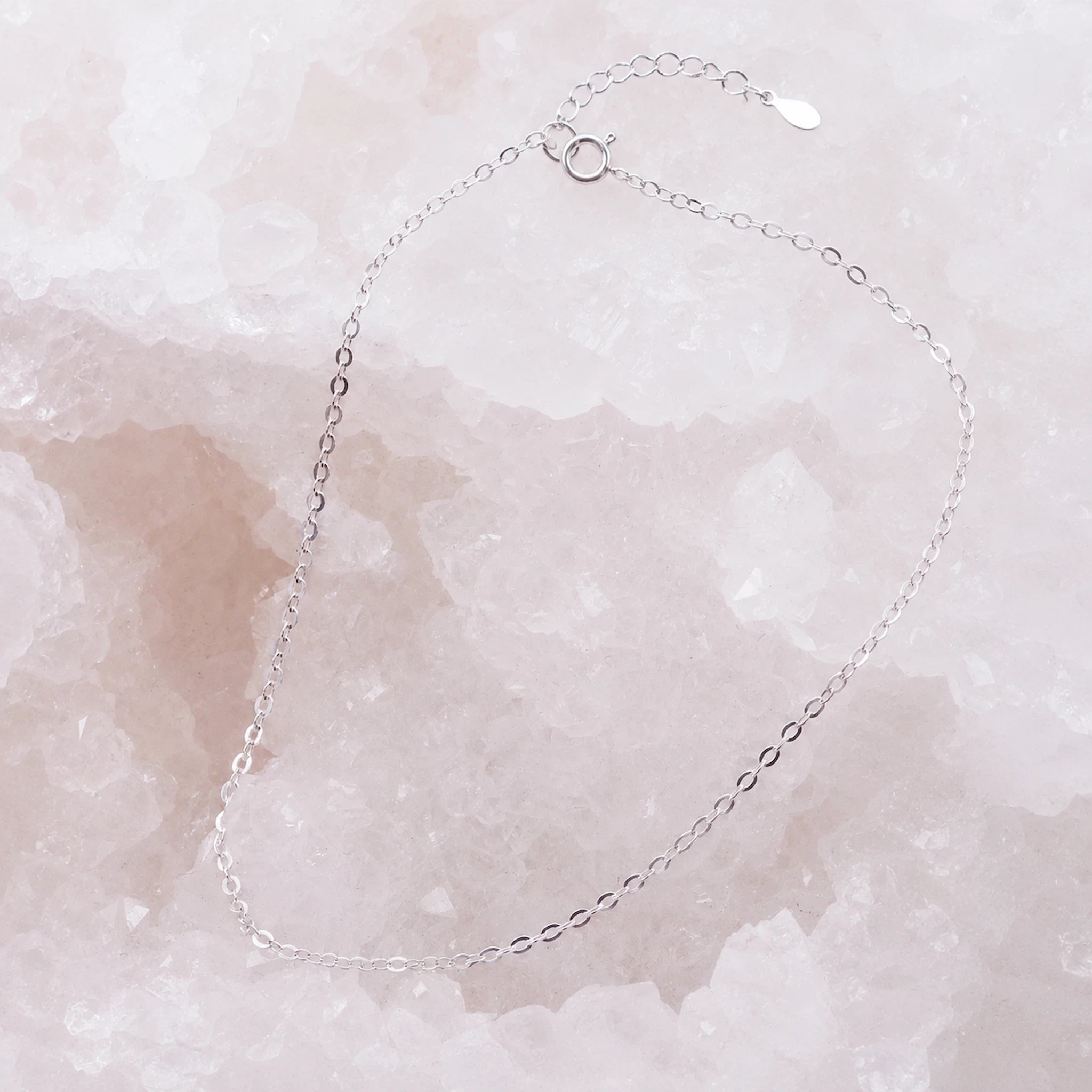 dainty italian sterling silver fine chain anklet laying on a white crystal
