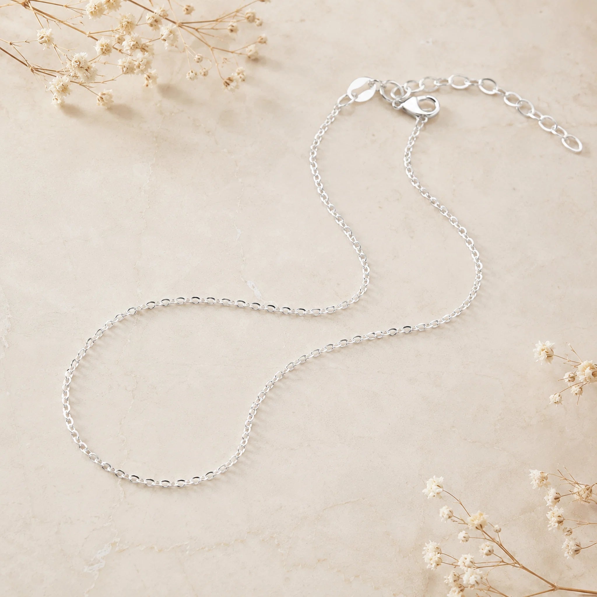 dainty italian sterling silver fine chain anklet laying on a light surface