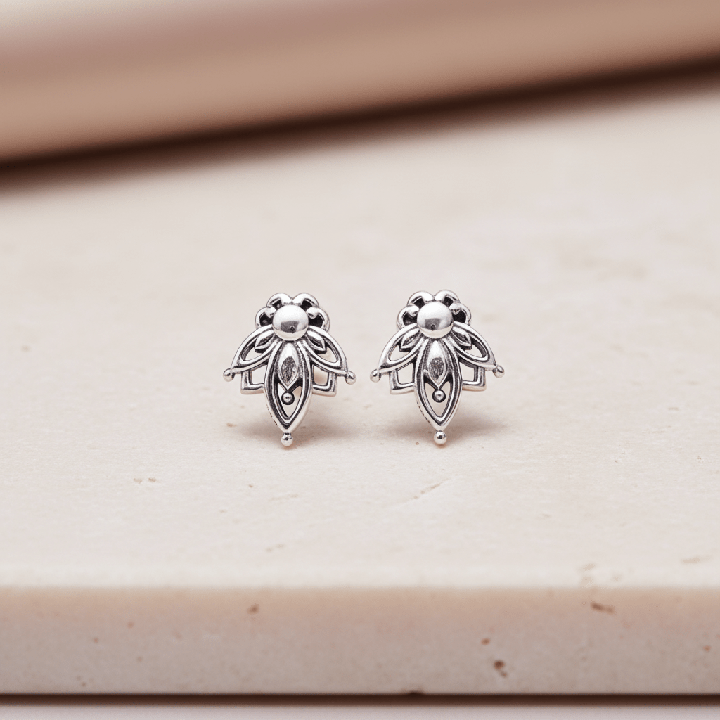 Pair of silver earrings on a beige surface