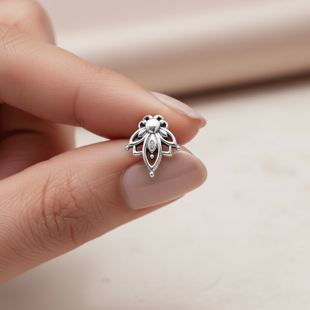 Silver lotus flower stud earring held between fingers against a neutral background