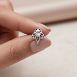 Silver lotus flower stud earring held between fingers against a neutral background