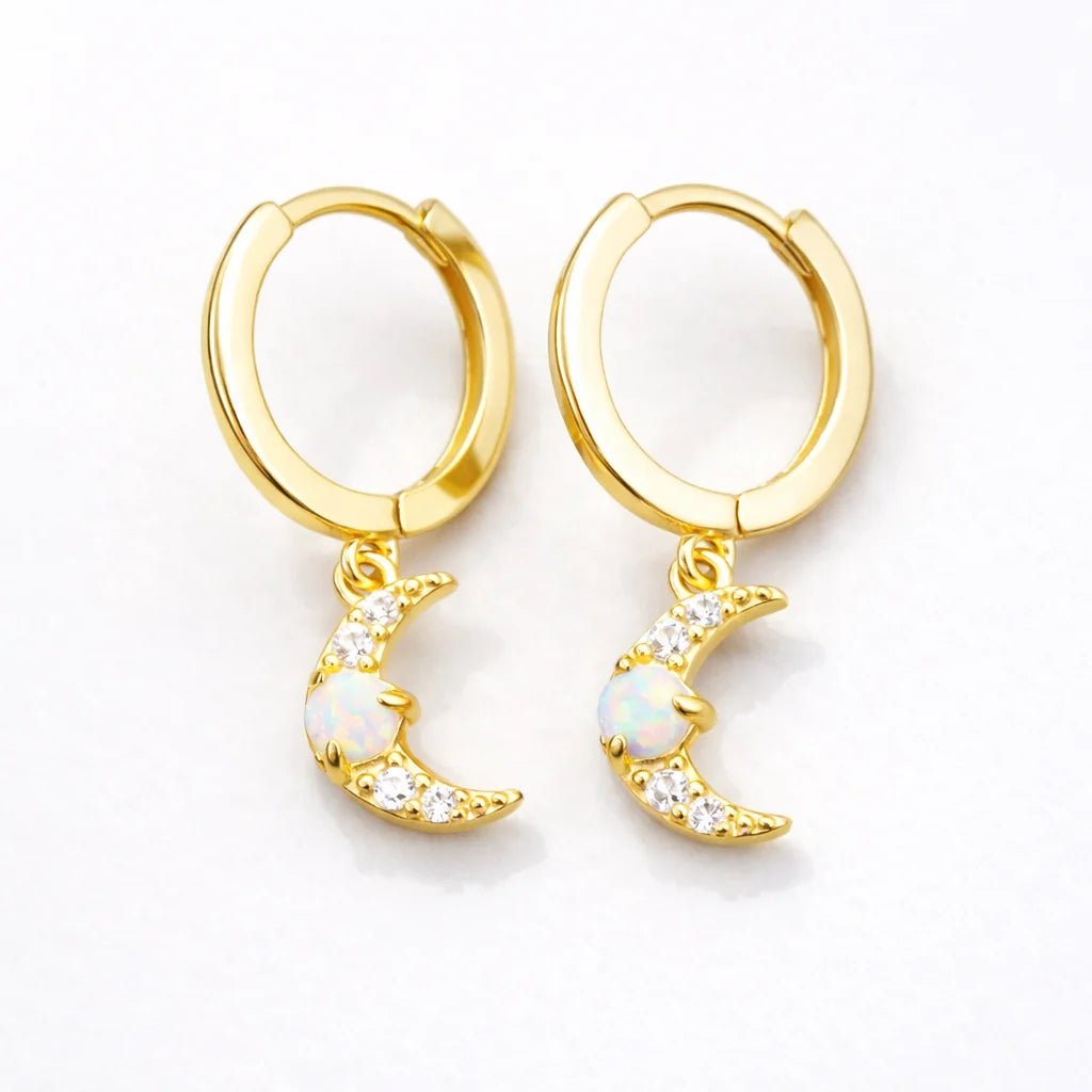 Gold hoop earrings with moon-shaped charms with opal and cubic zirconias on a white background