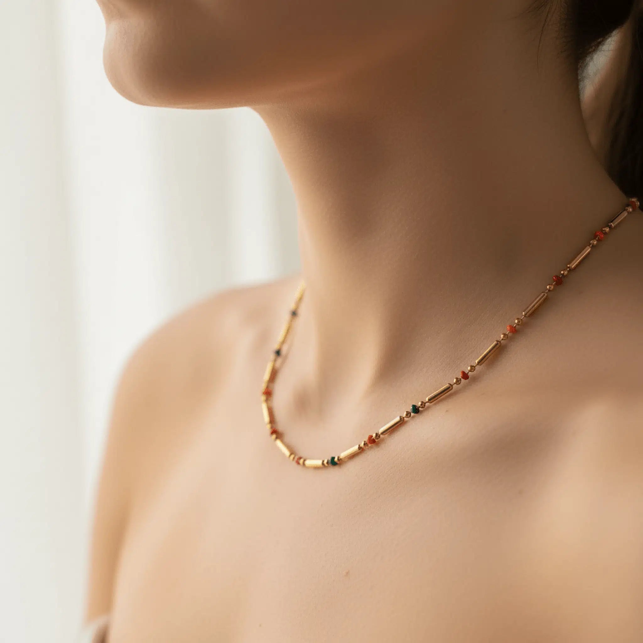 Necklace with colorful beads worn by a person against a neutral background