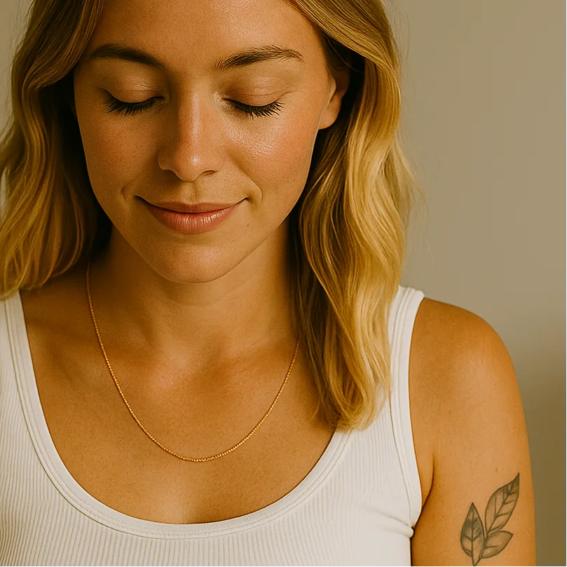 Woman wearing a dainty rose gold necklace with a neutral background