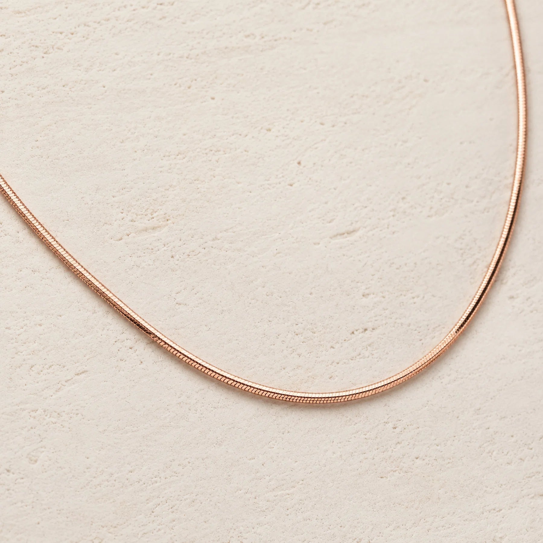 rose gold Snake chain Necklace on a wooden background