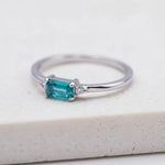 Dainty gold plated sterling silver gemstone ring with rectangular blue green tourmaline centre stone, round cubic zirconia side accents, and slim polished stackable band