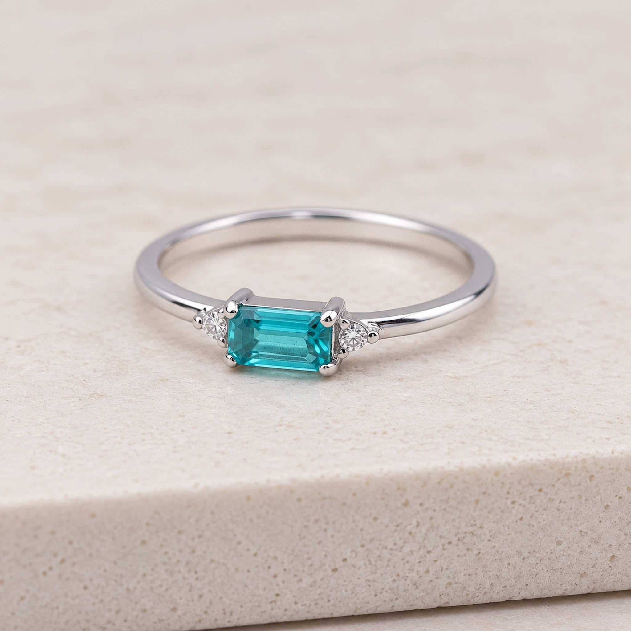 Dainty gold plated sterling silver gemstone ring with rectangular blue green tourmaline centre stone, round cubic zirconia side accents, and slim polished stackable band