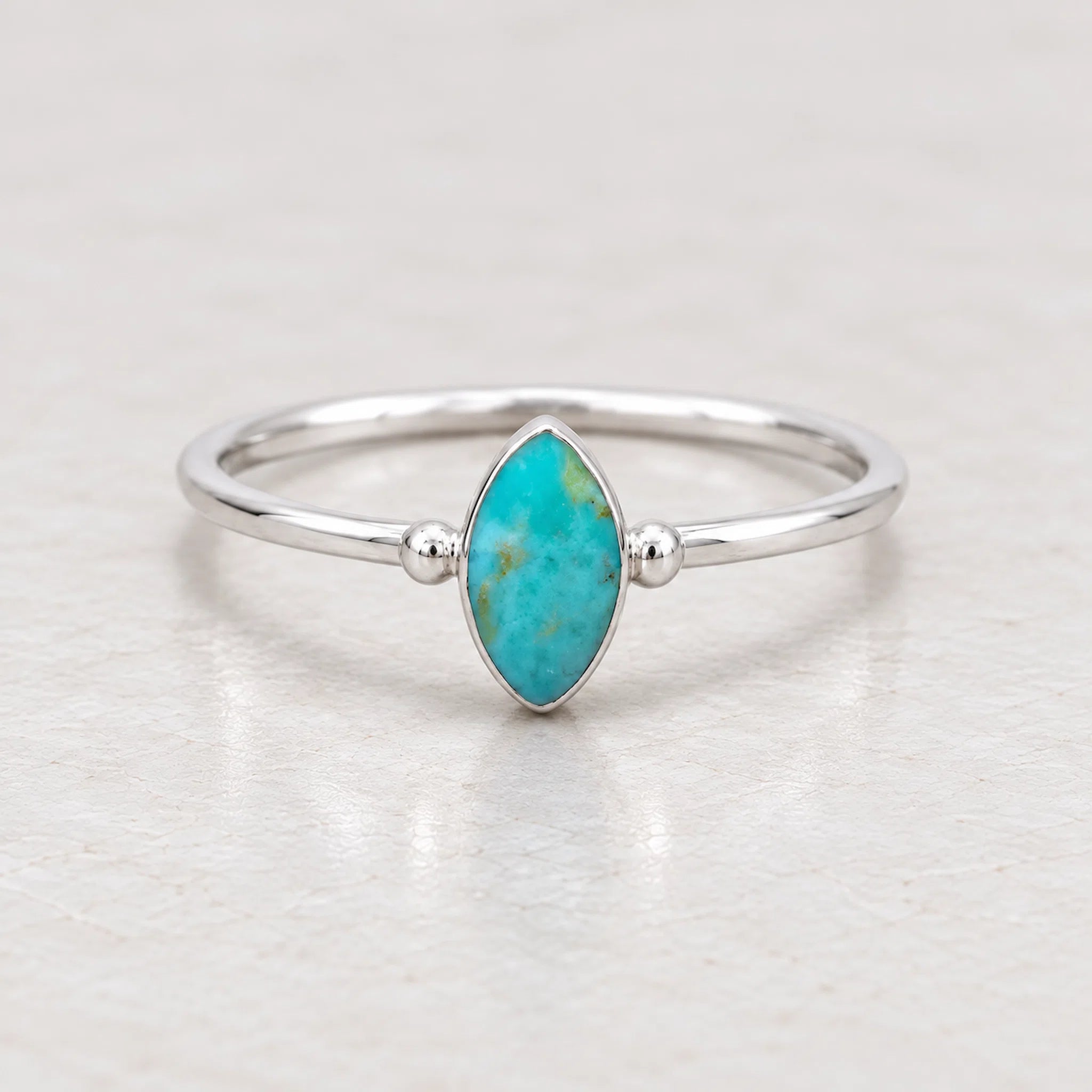 sterling Silver stacker ring with a turquoise stone on a beige surface with dried grass in the background