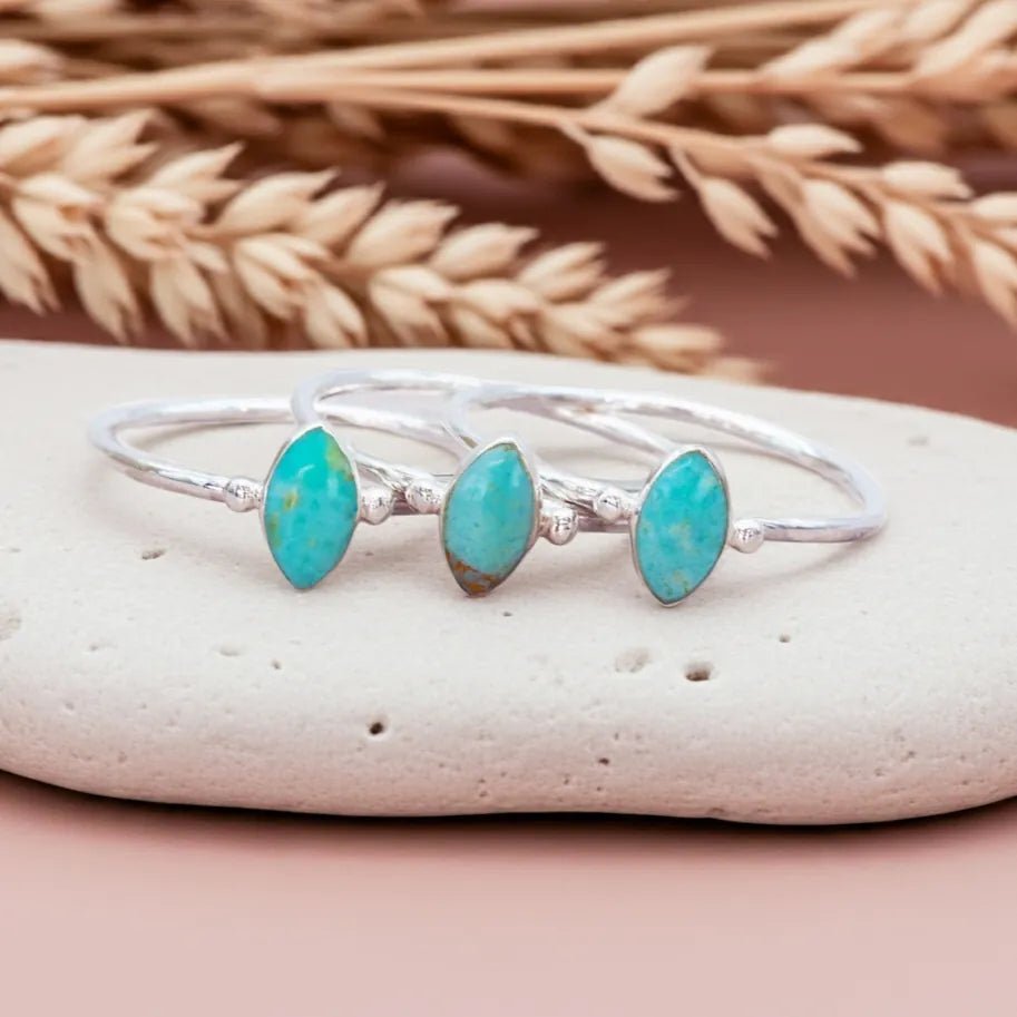 sterling Silver rings with turquoise stones on a pebble with dried wheat in the background