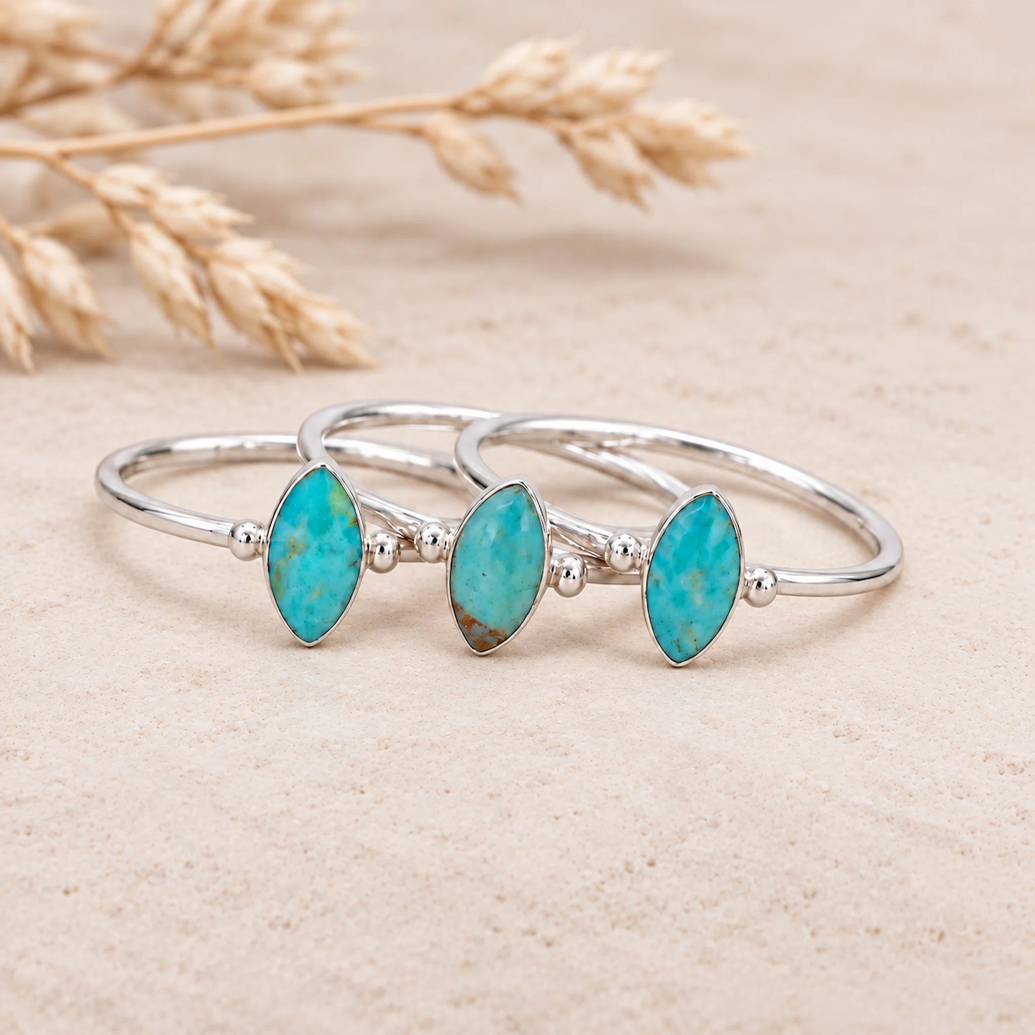 sterling Silver rings with turquoise stones on a pebble with dried wheat in the background