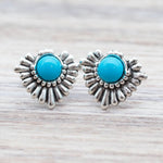 Silver earrings with turquoise stones on a wooden surface