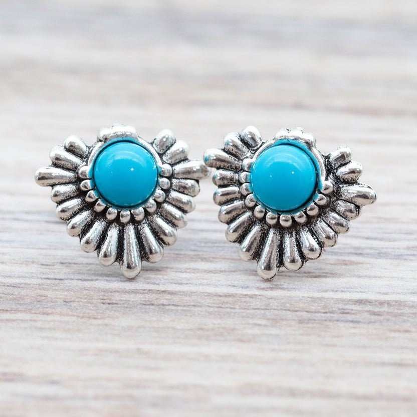 Silver earrings with turquoise stones on a wooden surface