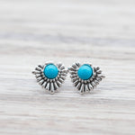 Pair of silver earrings with turquoise stones on a light wooden surface