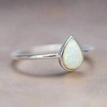 Dainty Sterling Silver ring with a teardrop-shaped white opal stone on a soft background