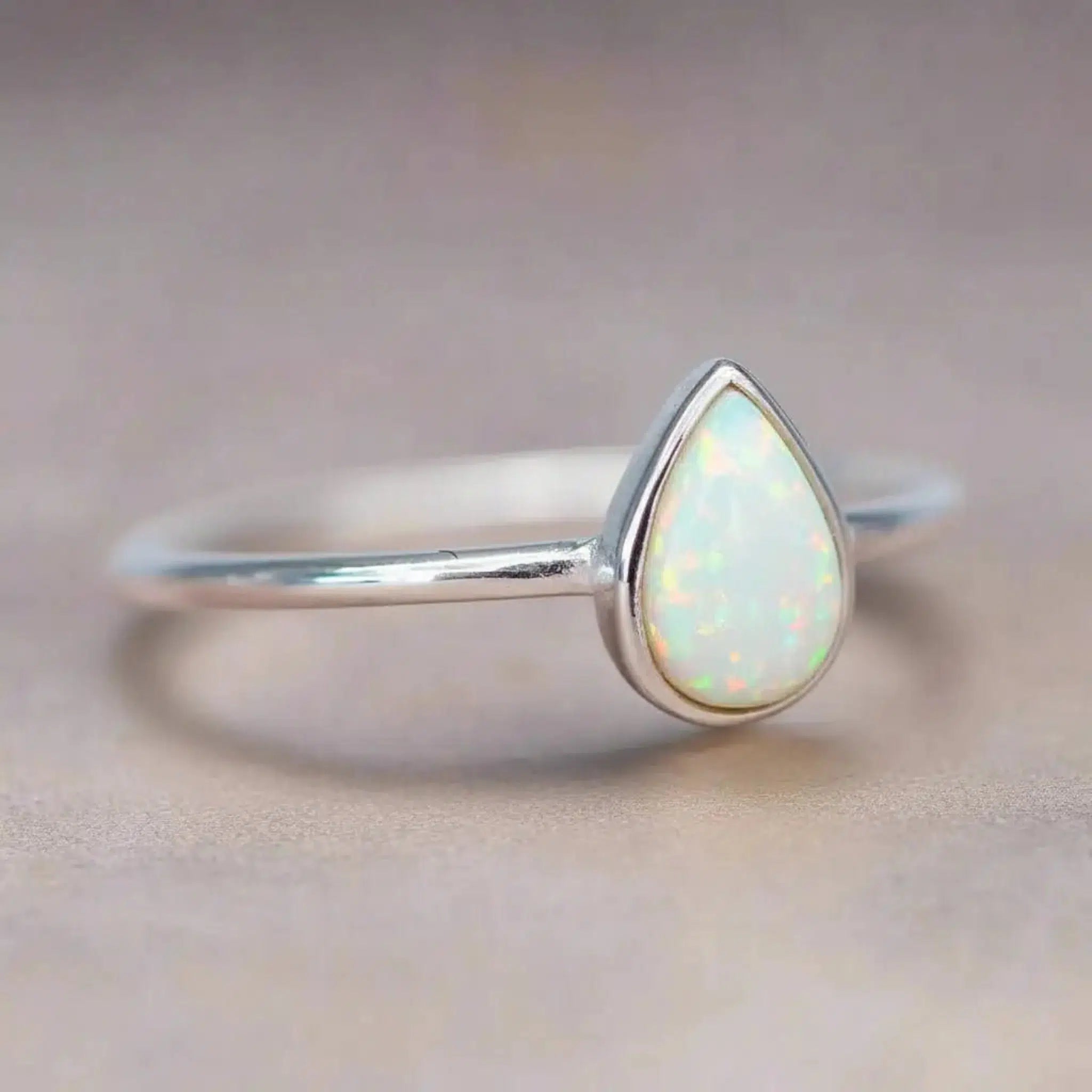 Dainty Sterling Silver ring with a teardrop-shaped white opal stone on a soft background