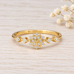 Gold snowflake stacking ring with cubic zirconia on a plain background