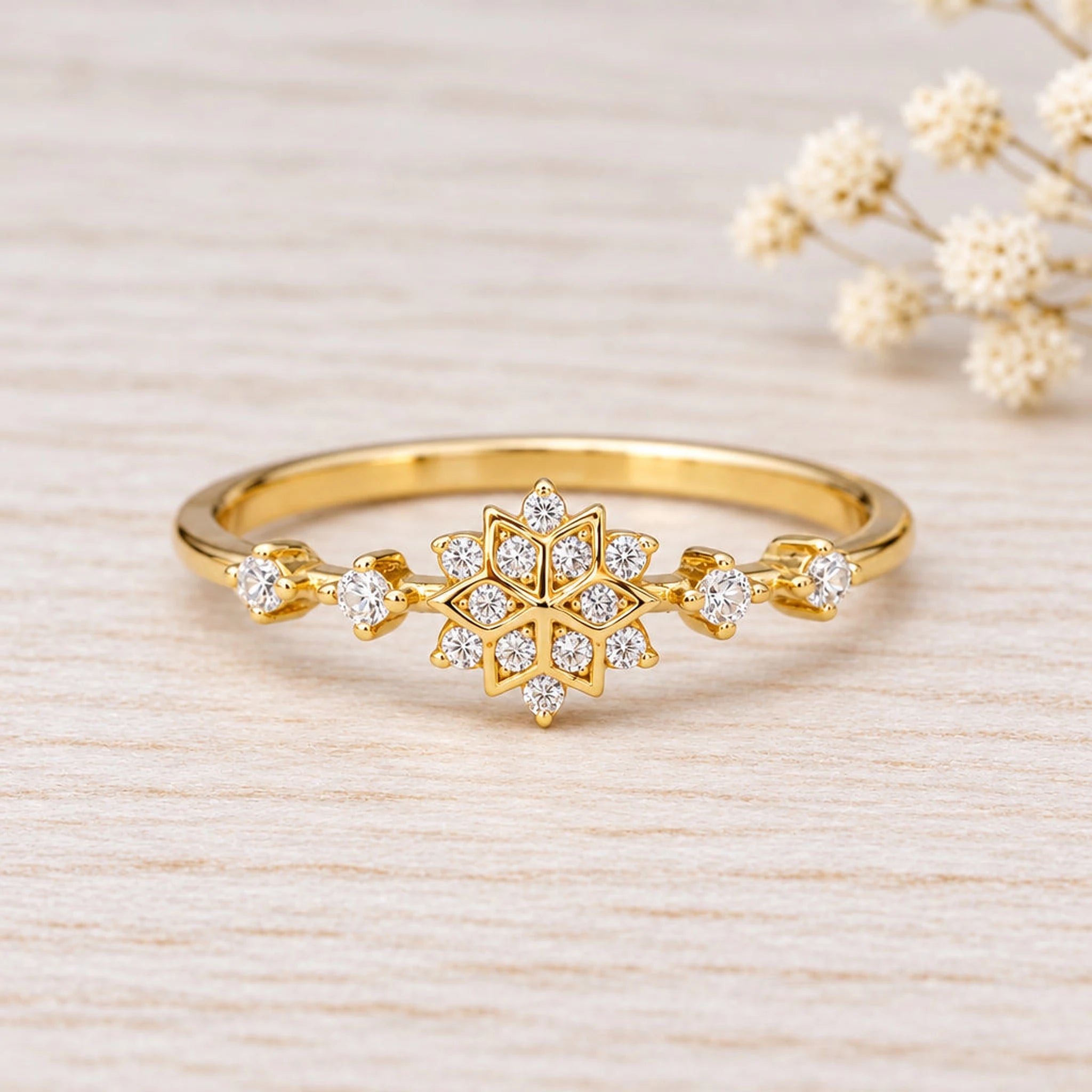 Gold snowflake stacking ring with cubic zirconia on a plain background