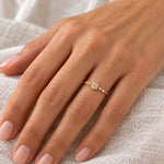 Dainty gold snowflake ring worn on a hand, showing the delicate snowflake centre and clear side stones