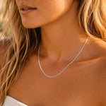 Close-up of a woman wearing a delicate silver necklace with a blurred background