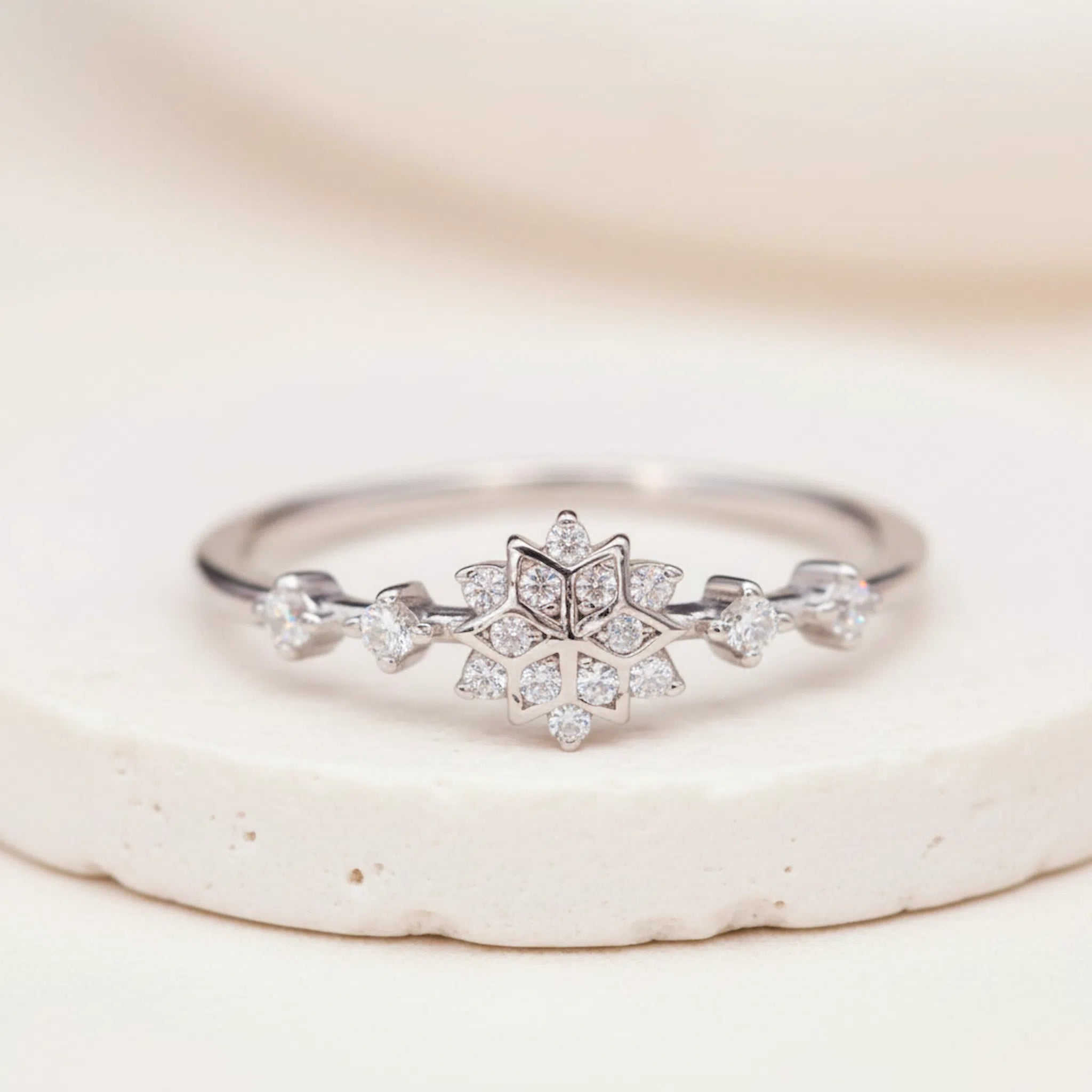 Sterling Silver ring with a delicate snowflake clear coloured cubic zirconia design on a white stone surface