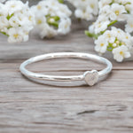 dainty sterling silver heart silver ring on a wooden surface