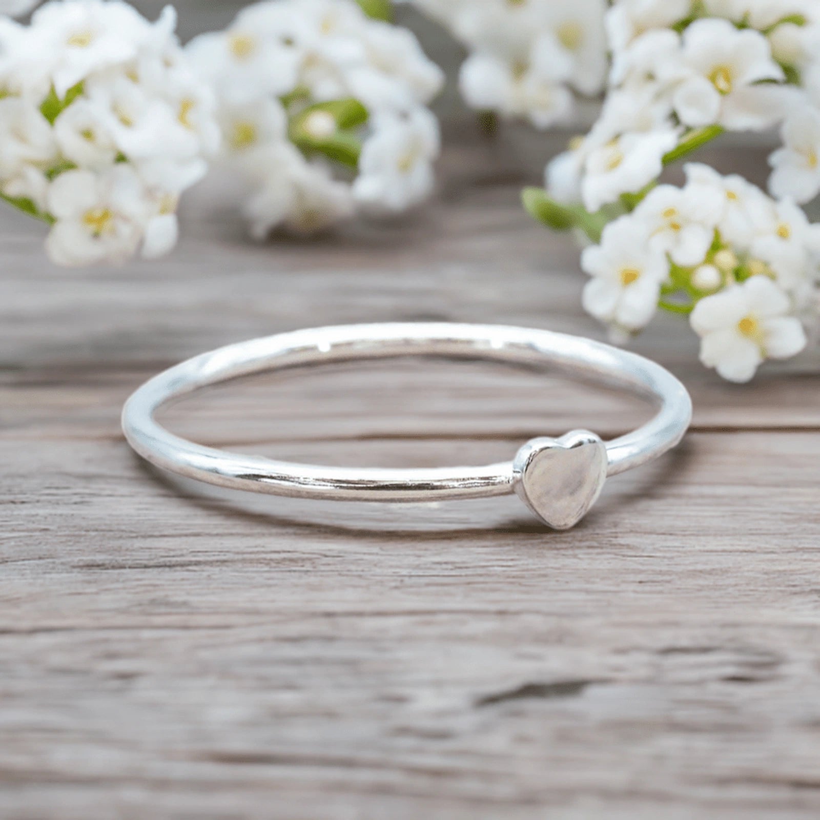dainty sterling silver heart silver ring on a wooden surface