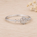 side view of a sterling silver ring with delicate snowflake design with cubic zirconias on a light background