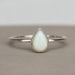 Sterling Silver ring with a teardrop-shaped white opal stone on a textured surface.