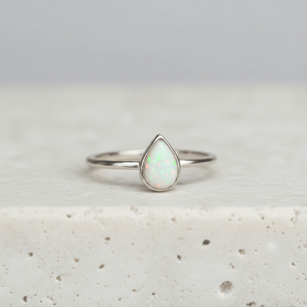 Silver ring with a teardrop-shaped opal stone on a light background