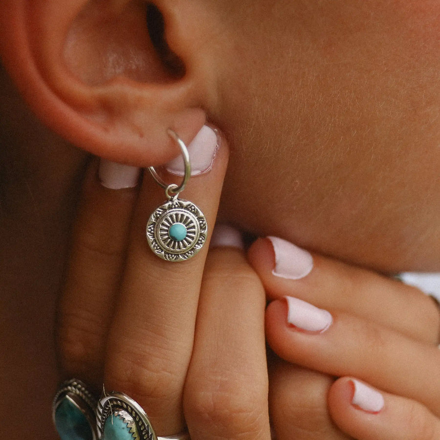 woman wearing dainty mandala earrings with a turquoise stone in the middle