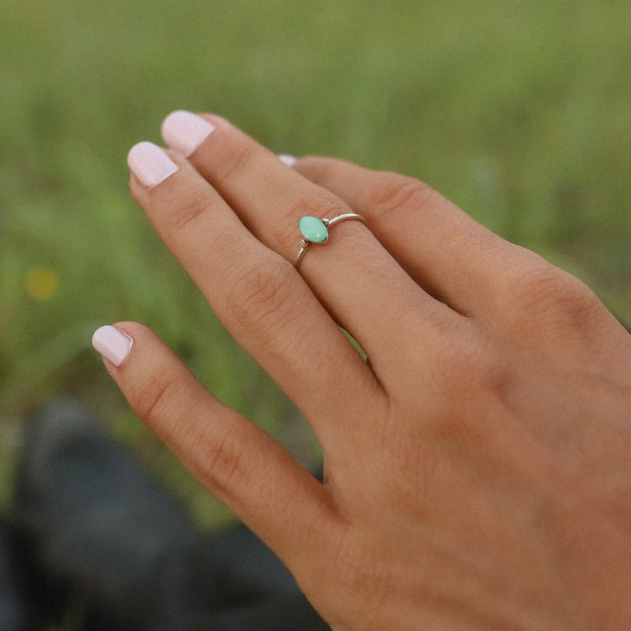 woman in a field wearing a sterling silver ring with a small turquoise stone