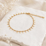 dainty gold waterproof anklet on a stone surface