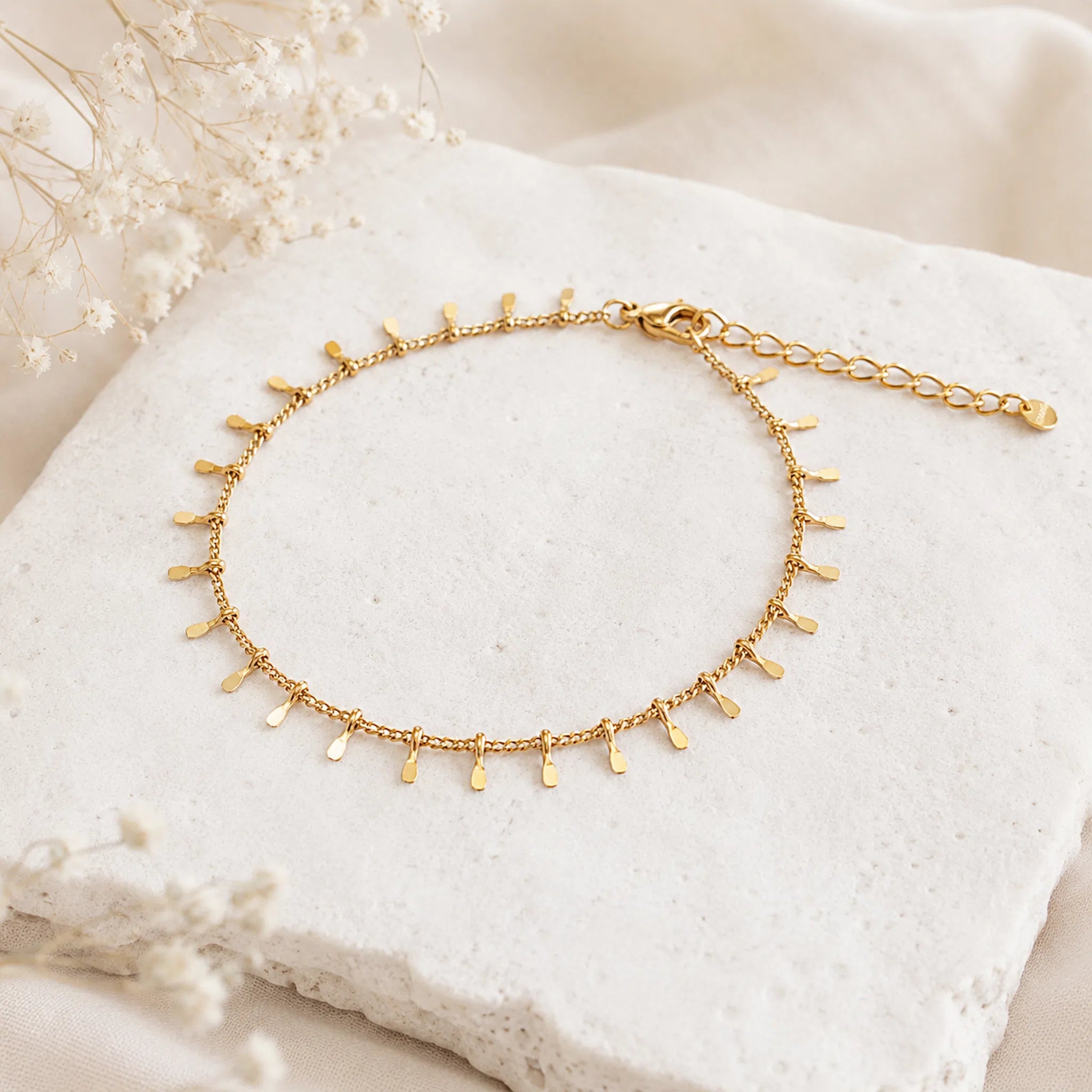 dainty gold waterproof anklet on a stone surface