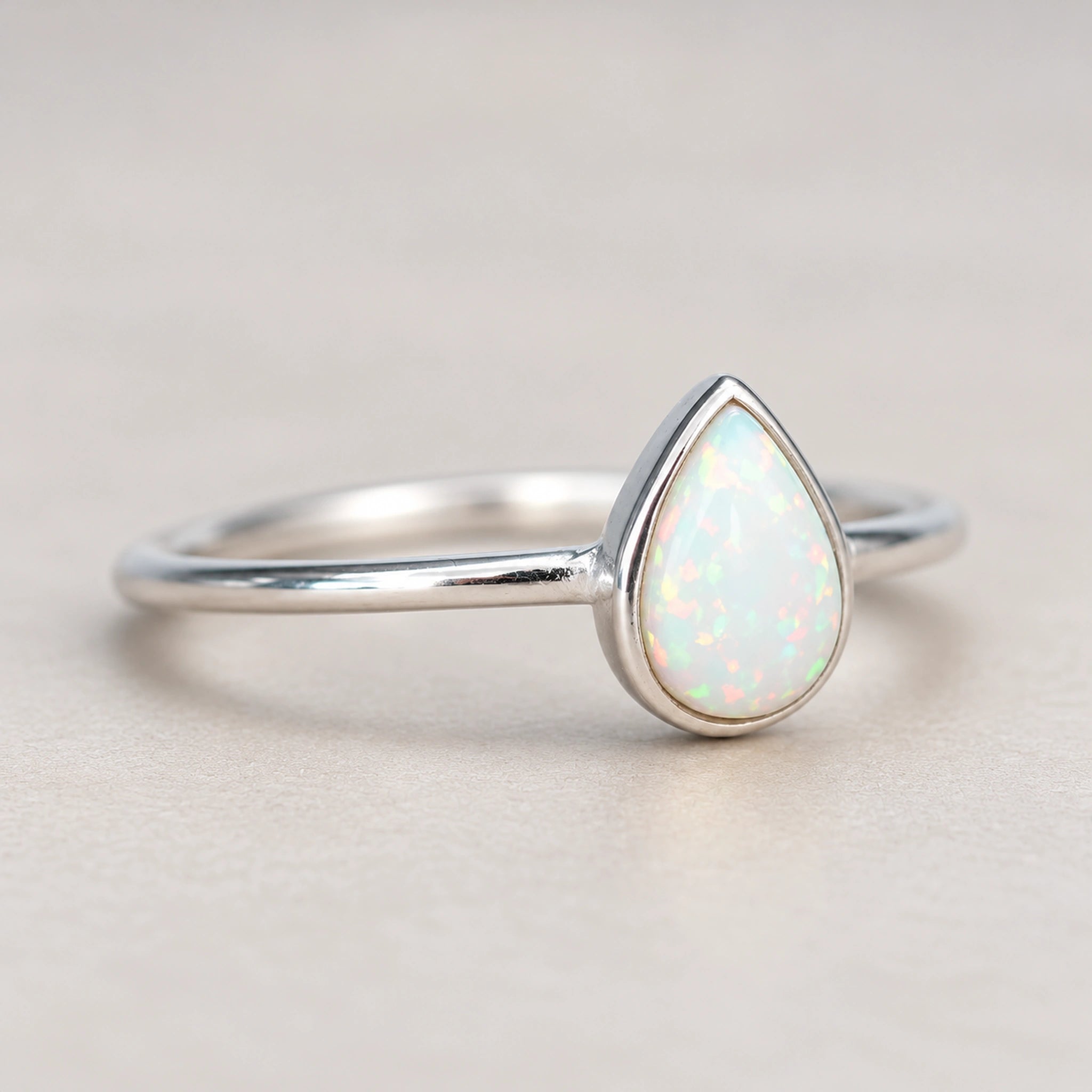 Angled view of the Dainty White Opal Teardrop Ring, showing its slim sterling silver band and smooth bezel setting.