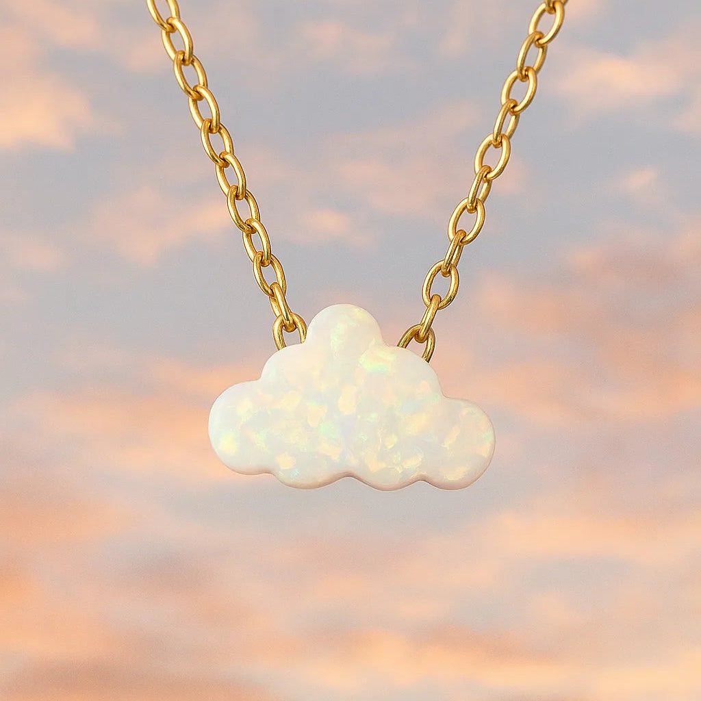 Opal cloud pendant necklace on a gold chain against a soft pink and orange sky background