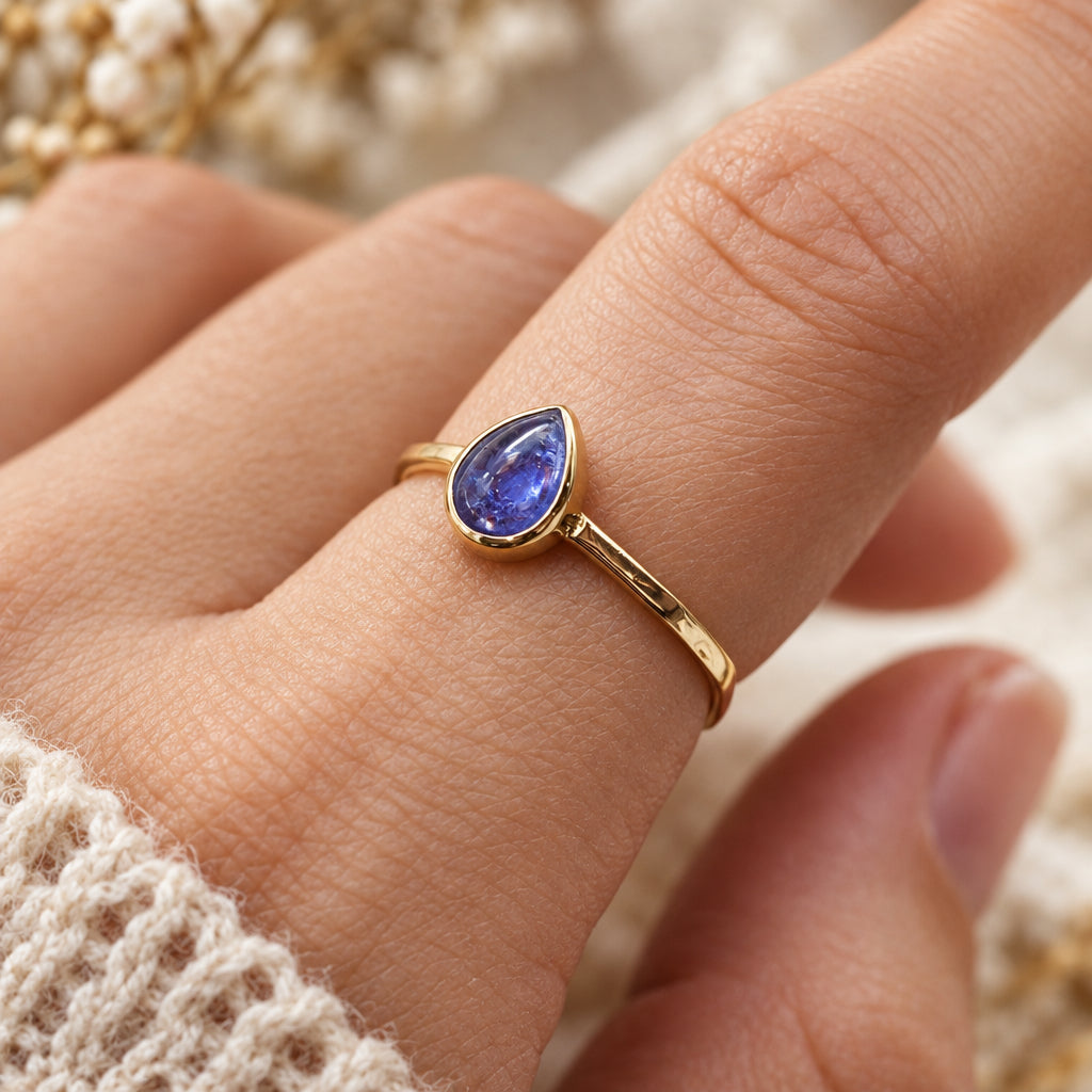 finger wearing gold december birthstone tanzanite ring by indie and harper