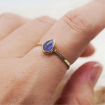finger wearing gold december birthstone tanzanite ring by indie and harper