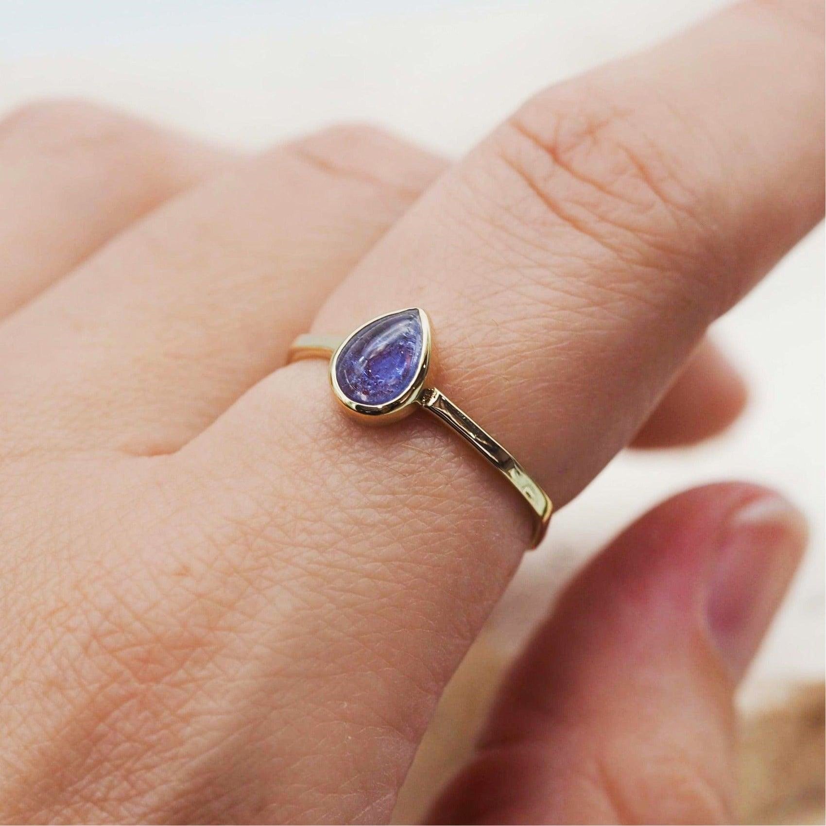 finger wearing gold december birthstone tanzanite ring by indie and harper