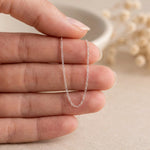 close up of a fine sterling silver cable chain necklace draped over fingers
