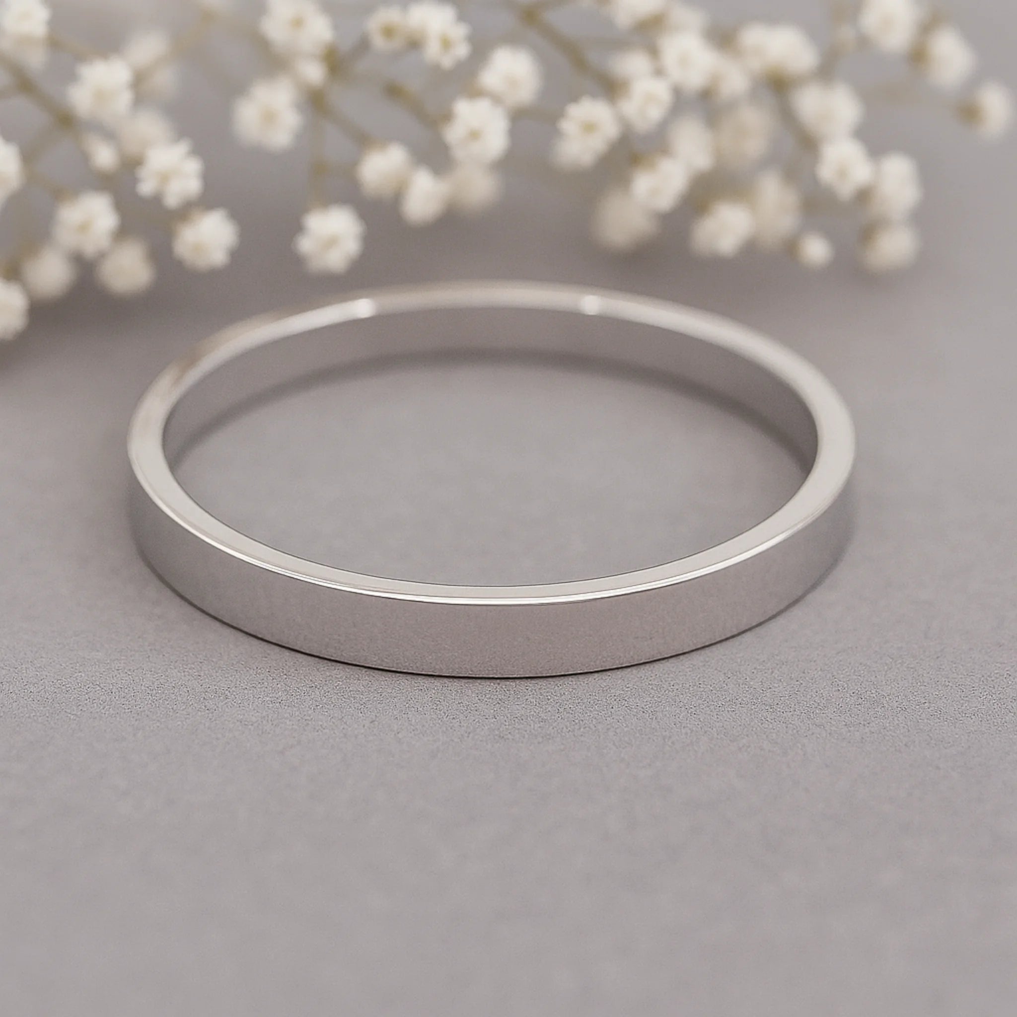 silver band ring on a grey surface with white babys breath
