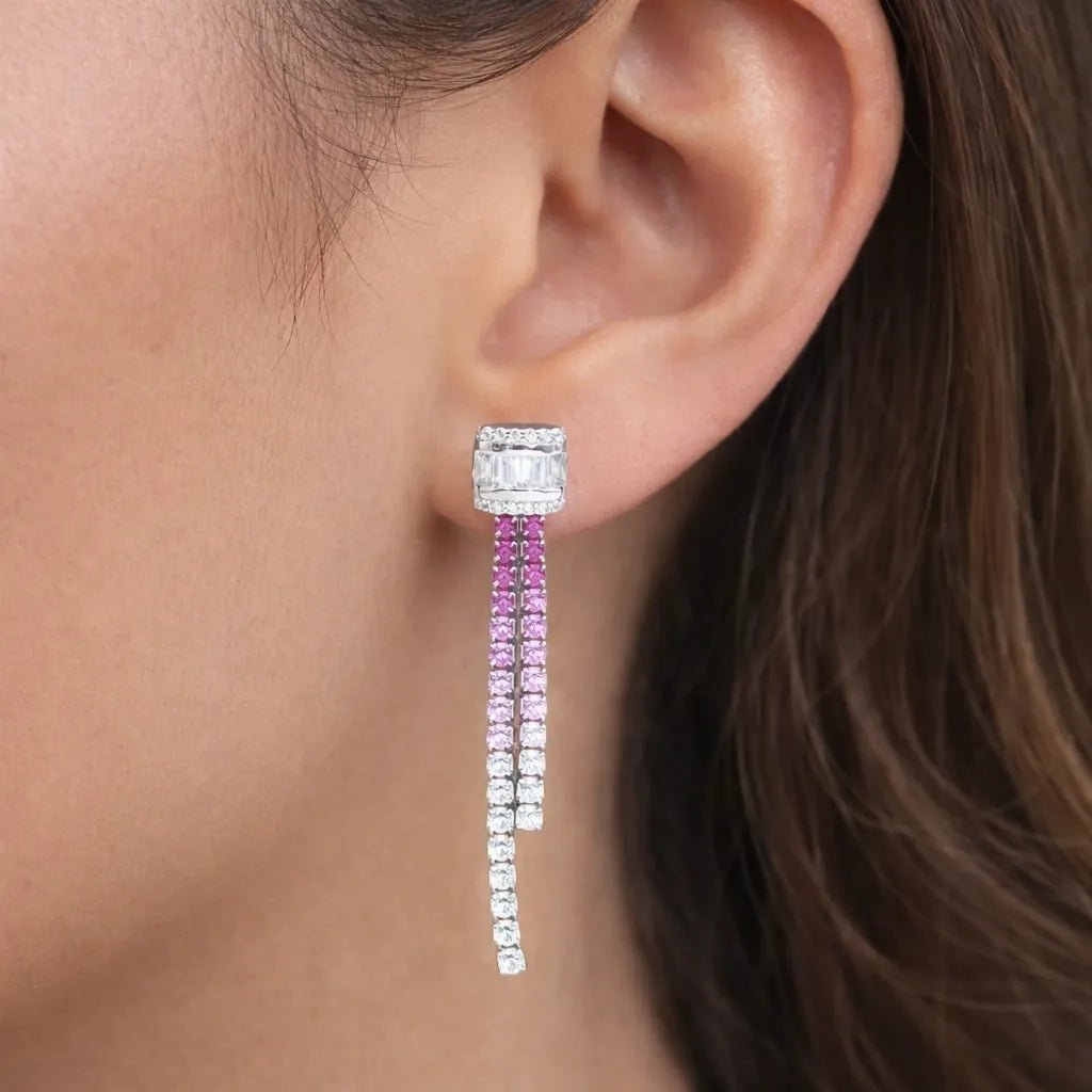 Close-up of an ear wearing a pair of diamond earrings with pink and clear stones.