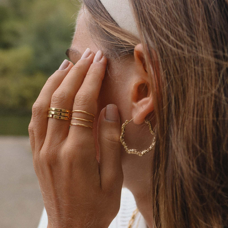 woman wearing gold stacker rings and gold earrings by indie and harper