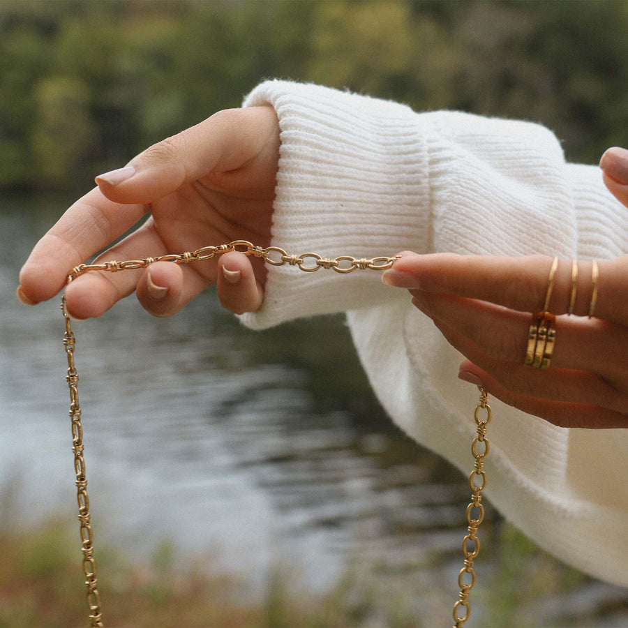 Woman holding a Gold Chain Necklace with a river behind - womens gold waterproof jewellery - Australian jewellery brand