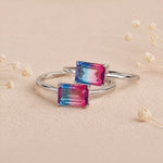 Two Sterling Silver Rings with an emerald cut Cotton Candy Tourmaline Gemstone with blue and pink colours on a soft light surface.