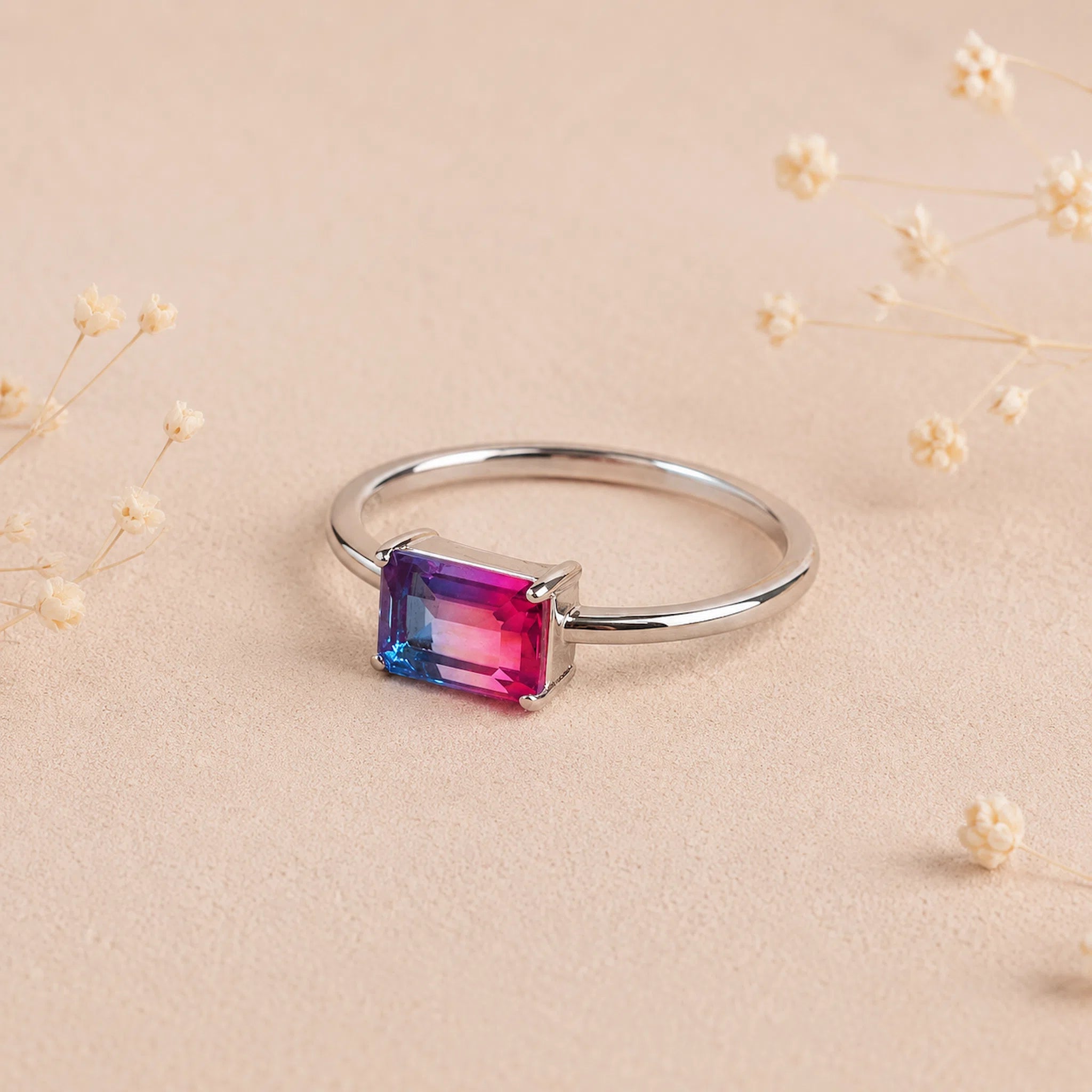 side view of a Sterling Silver Ring with an emerald cut Cotton Candy Tourmaline Gemstone with blue and pink colours on a soft light surface.