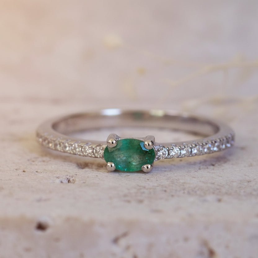 Silver ring with a green gemstone on a textured beige background