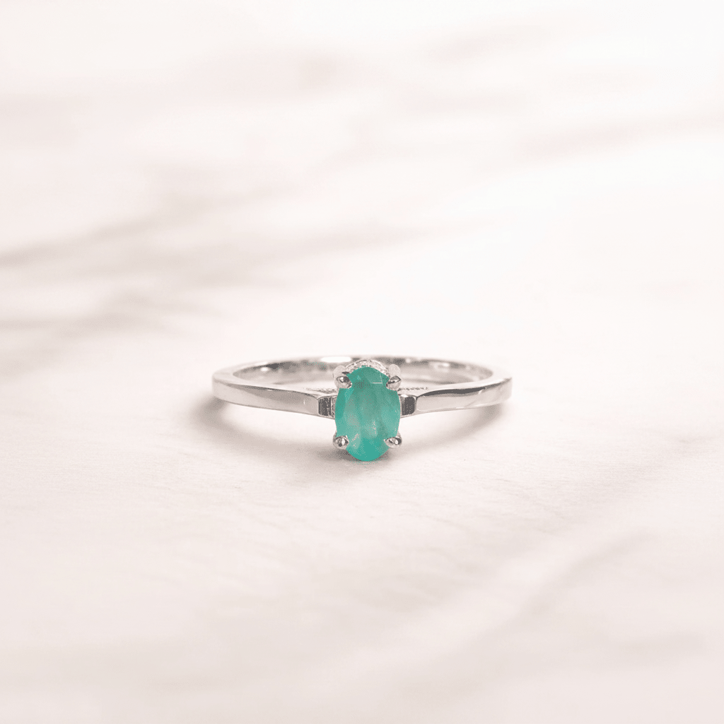 Silver ring with a green gemstone on a light pink background