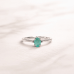 Silver ring with a green gemstone on a light pink background