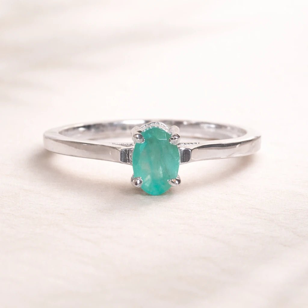 Sterling Silver ring with a oval solitaire claw set natural emerald gemstone on a light background